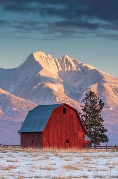 a red barn sitting in the middle of a field