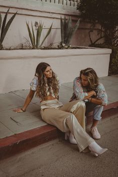 two young women sitting on the sidewalk next to each other