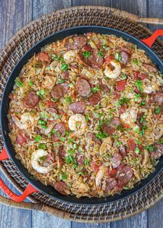 a skillet filled with shrimp, sausage and rice on top of a wooden table