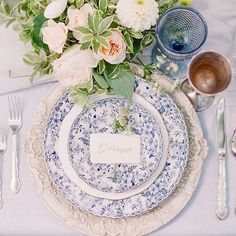 a table set with plates, silverware and flowers