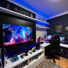 a gaming room with two large monitors and several video game controllers on the desks