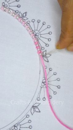 someone is stitching something with pink thread and beads on the side of a t - shirt