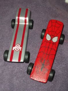 two toy skateboards with spider - man designs on them, one red and the other silver