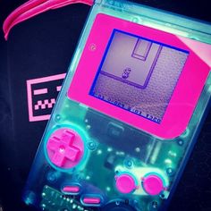 a pink and blue gameboy sitting on top of a bag