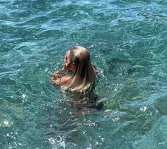 a woman swimming in the ocean with her hair blowing back and looking at something off to the side