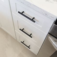 an image of a kitchen setting with white cupboards and black handles on the drawers