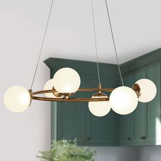 a chandelier hanging from the ceiling in a kitchen with green cabinets and cupboards