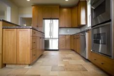 an empty kitchen with stainless steel appliances and wood cabinetry on the walls is shown