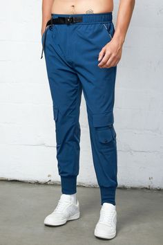 The Blaze Golf Joggers provide functional yet stylish workout cargo pants for all your active needs. With added features such as cargo pockets for storage, golf tee loops, and a belt for a secure fit, these joggers are perfect for any active lifestyle. 87% Nylon 13% Spandex Model is 6'2" and wearing a size medium Blue Sports Bottoms With Cargo Pockets, Sports Techwear Cargo Pants With Side Pockets, Techwear Cargo Pants With Side Pockets For Sports, Sportswear Cargo Pants For Outdoor Activities, Functional Sweatpants With Cargo Pockets For Outdoor, Functional Cargo Pants For Jogging, Sportswear Cargo Pants With Side Pockets For Outdoor Activities, Sportswear Cargo Pants With Side Pockets For Outdoor, Functional Cargo Style Sports Pants