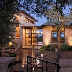 a house that is lit up at night with lights on the windows and stairs leading to it