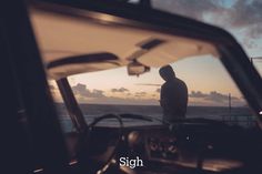 a man standing in front of a car next to the ocean at sunset or dawn