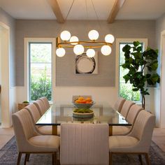 a dining room table with chairs and a bowl of fruit on the glass top in front of it