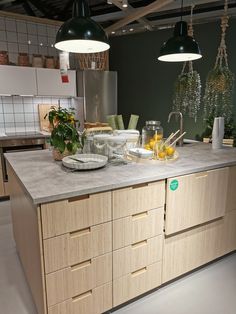 a kitchen with lots of counter space and hanging lights above the island in front of it