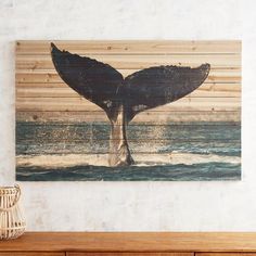 a painting of a whale's tail in the ocean on a wooden wall above a dresser