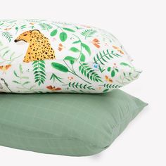 two pillows on top of each other, one with a cheetah and the other with leaves