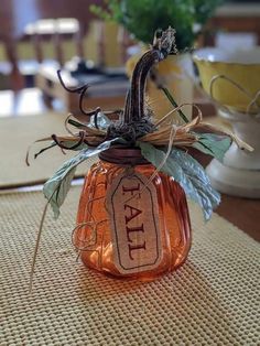 a glass jar filled with leaves sitting on top of a table