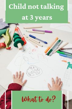 a child's hands with crayons and pencils on the table