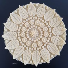 an intricately designed piece of art made out of white beads and leaves on a black background