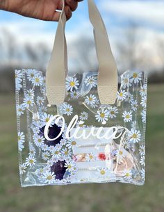 a hand holding a clear bag with flowers on it and the words believe written in white