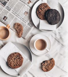 cookies and coffee are on the table next to newspapers