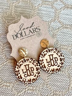 leopard print earrings with the initials j and p on them, sitting on a table