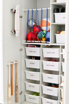 a white closet filled with lots of bins next to a baseball bat and glove