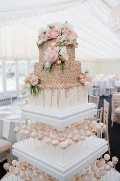 three tiered wedding cake with pink flowers and greenery on top, surrounded by white tablecloths