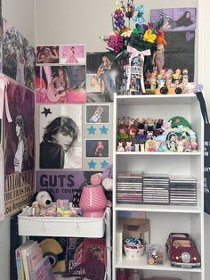 a white book shelf filled with lots of toys and pictures next to a wall covered in photos