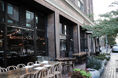 tables and chairs are lined up on the side walk in front of an outdoor restaurant