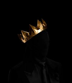 a man wearing a gold crown on top of his head in front of a black background