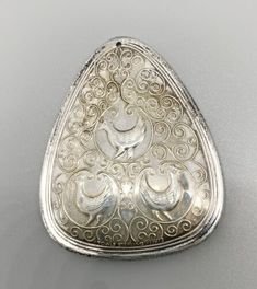 an ornate silver brooch with two birds on it