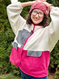 a woman wearing glasses and a pink hat is posing for the camera with her hands on her head