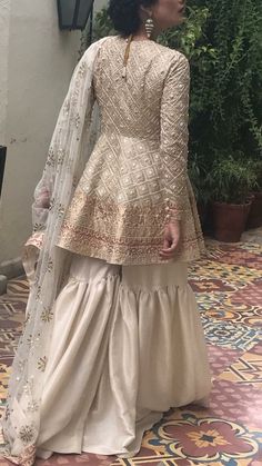 the back of a woman's wedding dress in beige and white with gold embroidery on it