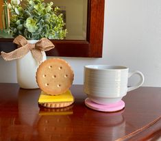 a cookie sitting on top of a wooden table next to a cup and saucer