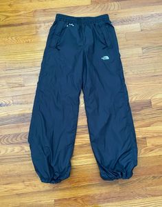 North Face Women Windwall Hydrenaline Woven Windproof Pants Style #: NF0A531X Material: 100% Polyester Zippered Hand and Rear Pockets Full Mesh lining Elastic Waist Pant Cuff Toggle Cords COLOR: black SIZE: small MEASURES APPROXIMATELY (GARMENT LAYING FLAT) 14" Waist, stretches to 17" 41" Outseam 30" SLEEVE LENGTH / inseam PURCHASE OF ANY ITEM IMPLIES CONSENT OF BUYER TO THESE TERMS. BE AWARE THAT YOUR DISPLAY/PHONE MAY NOT REPRESENT THE TRUE COLOR OF AN ITEM. I do NOT offer free returns for siz Plain Leggings, Rhinestone Embroidery, Waterproof Pants, Waist Stretches, It Services, Nike Vintage, Pants Style, Clothing Manufacturer, Cuffed Pants