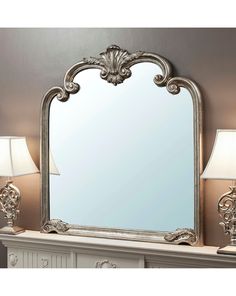 a large mirror sitting on top of a mantle next to lamps and lampshades