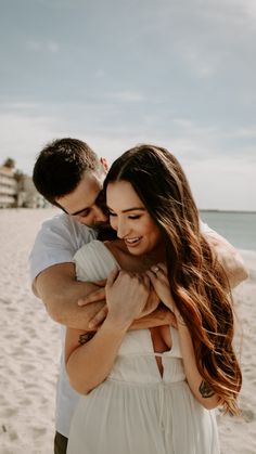 a man and woman hugging on the beach