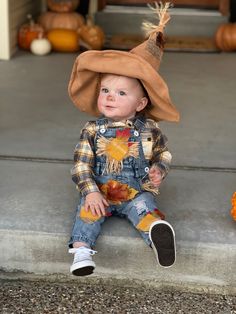 a little boy sitting on the steps wearing a scarecrow hat