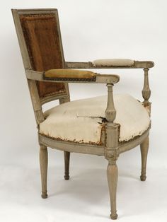 an old wooden chair with a cushion on it's back and armrests