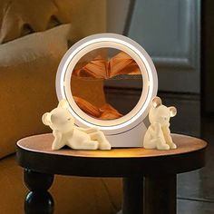 two small white bears sitting on top of a wooden table next to a round mirror