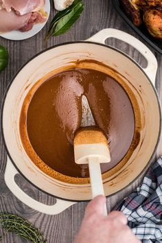 a person mixing chocolate in a bowl with a spatula on the side and green peppers around it