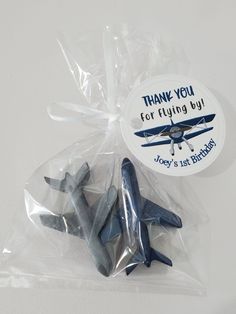 two toy airplanes in plastic bags on a white surface with thank you for flying by stickers