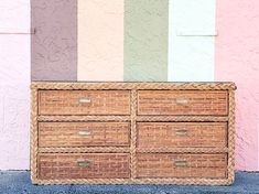 a wicker dresser with four drawers in front of a colorful wall