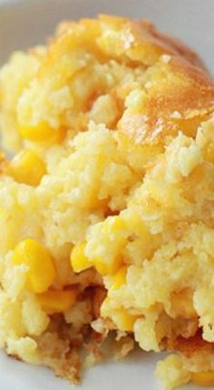 a close up of a plate of food with corn on it and another piece of cake in the background