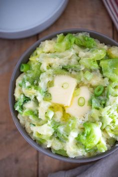 a bowl filled with mashed potatoes and broccoli on top of a wooden table