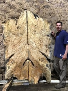 a man standing next to a large piece of wood