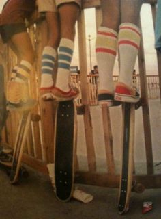 three people standing on skateboards with their feet up in the air and one person wearing striped socks