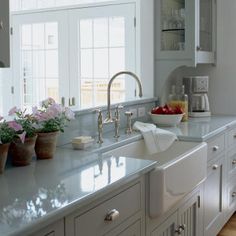 a kitchen filled with lots of white cabinets and counter top space next to a window