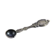 a silver spoon with a black bead on the side and an ornate design in the middle