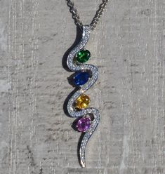 The Zuri Ladies Contemporary Multi-stone and Diamond Drop Necklace. Dangling from a 16 inch white gold chain is a 1.5 inch 14 karat white gold pendant. Add a pop of color to your outfit with this unique and modern necklace. The chain can be swapped for another length chain (shorter or longer) for an additional charge. Each piece has been hand selected and meticulously identified and graded by a Graduate Gemologist who has been awarded a degree by the Gemological Institute of America (GIA). Pleas Platinum Pendant Necklace With Gemstone, Platinum Gemstone Pendant Necklace, Sterling Silver Necklaces With Stones In White Gold, White Gold Sterling Silver Necklaces With Stones, Modern Multi-stone Cubic Zirconia Jewelry, White Gold Sterling Silver Necklace With Stones, White Gold Pendant Necklaces With Stones, Platinum Multi-stone Jewelry Gift, Platinum Multi-stone Jewelry For Gift